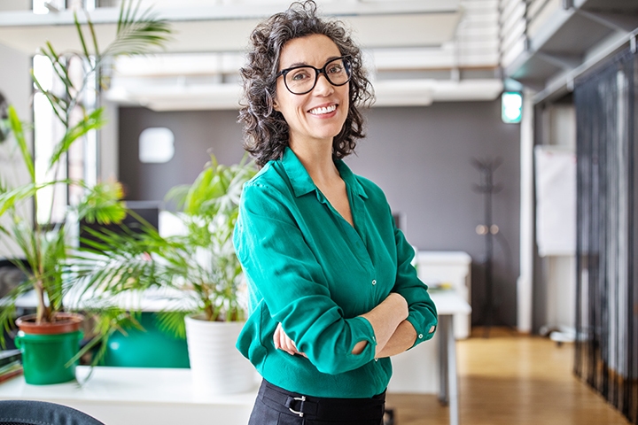 Portrait of happy mature businesswoman standing with her arms crossed