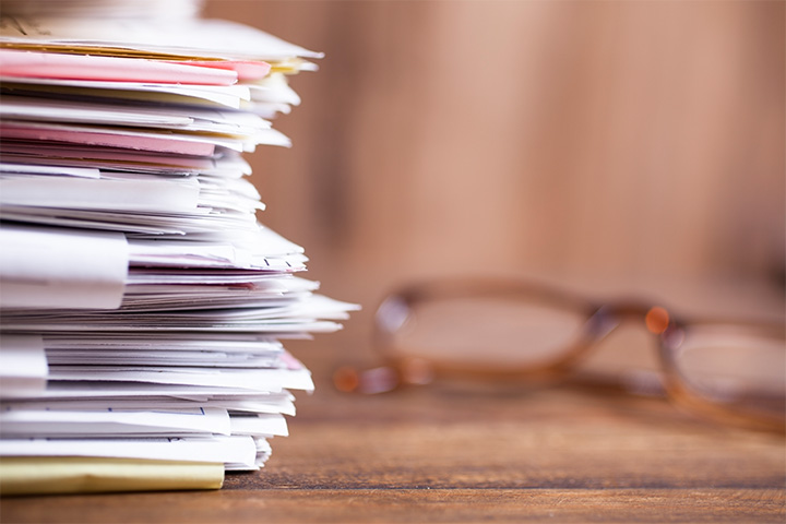 close up shot of a stack of paper with a pair of glasses behind it