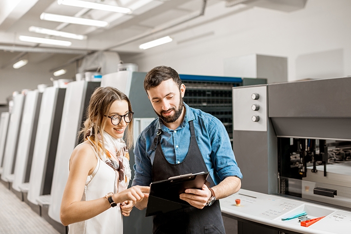 woman designer and print operator working with printing machines