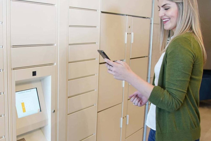 Woman collecting item at parcel locker with cell phone
