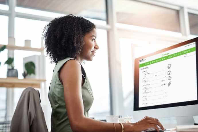 a brunette woman using a web tracking software on iMac in a bright office with high windows