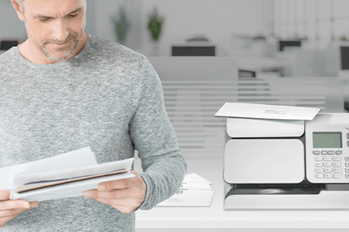 Person looking at a letter next to a franking machine